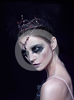 Portrait of the ballerina in the role of a black swan on black background