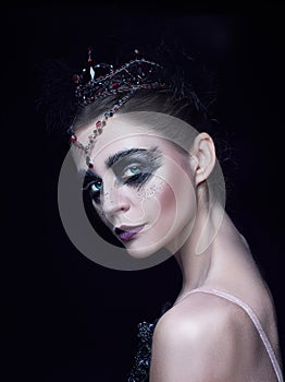 Portrait of the ballerina in the role of a black swan on black background