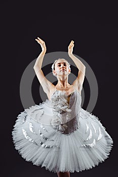 Portrait of the ballerina in the role of a white swan on grey background. Beautiful, attractive, young, graceful girl