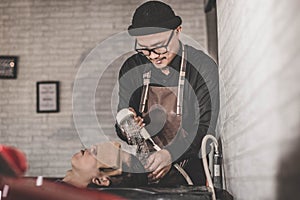 Portrait of barber washes costumer hair who relaxed in the chair sink