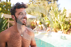 Portrait Of Bare Chested Hispanic Man Outdoors With Friends Enjoying Summer Pool Party