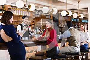 Portrait of barman and people who are standing near bar counter in luxurious restaurant