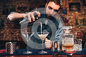 Portrait of barman pouring fancy cocktail in bar at party. Manhattan cocktail beverage in nightclub