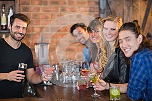 Portrait of bartender serving drinks to happy customers