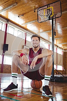 Portrait of basketball player sitting on ball