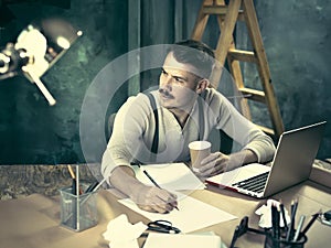 Portrait of a bearded businessman who is checking details of his upcoming meeting in his notebook and typing.