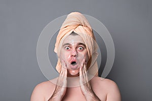 Portrait of bearded funny man applying white mask to his face