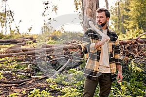 Portrait of bearded guy is getting ready for work trees cutting in forest, alone