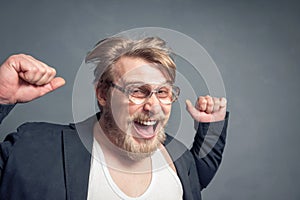 Portrait of a bearded guy with glasses, tousled hair, clenched fists, and a contented face