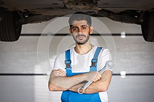 Portrait of bearded handsome automotive mechanic man standing in garage. Vehicle service manager worker work in