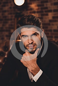 Portrait of bearded handsome minded businessman in black suit touching chin