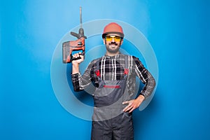 Portrait of bearded handyman with electric drill isolated on blue background