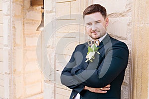 Portrait of a bearded hipper groom in a blue suit and a red tie at a wedding walk photo