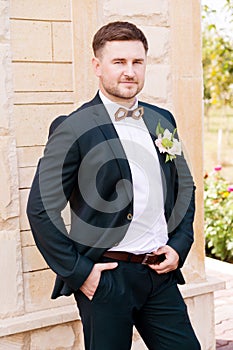 Portrait of a bearded hipper groom in a blue suit and a red tie at a wedding walk photo