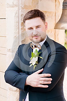 Portrait of a bearded hipper groom in a blue suit and a red tie at a wedding walk photo