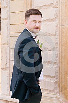 Portrait of a bearded hipper groom in a blue suit and a red tie at a wedding walk photo