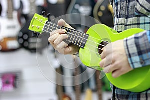 Portrait of a bearded hipster male in red hat playing on ukulele.