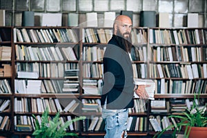 Portrait of bearded hipster man iwith books n library photo