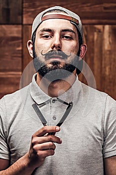 Portrait of bearded hipster with straight edge razor