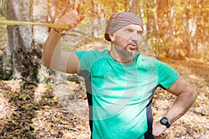 Portrait of a bearded man in age stands near a taut slackline in an autumn forest