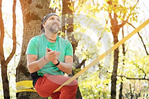 Portrait of a bearded man in age stands near a taut slackline in an autumn forest