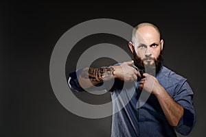 Portrait of a bearded man cutting his beard with scissors