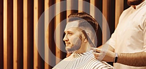 Portrait of bearded man with fashionable hairstyle in profile men hairdresser. Free area for text