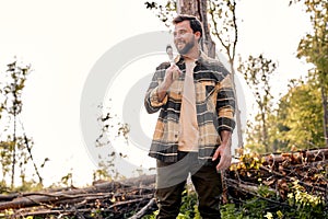 Portrait of bearded man is getting ready for work trees cutting in forest, alone