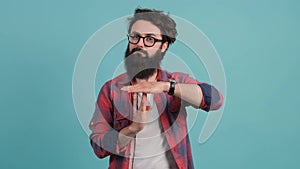 Portrait of a bearded man making the time out gesture, asking for a break.