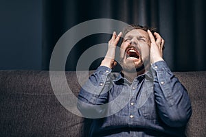 Portrait of bearded man screaming desperately in dark