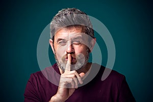 A portrait of bearded man showing hush gesture. People and emotions concept