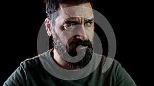 Portrait of bearded man sitting with serious face looking at the camera.