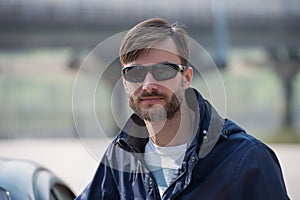 Portrait of a bearded man wearing sunglasses in a park.