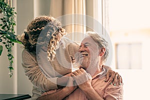 Portrait of bearded senior man looking at his middle-aged daughter, spending time together at home