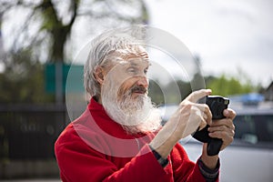 Portrait of bearded senior man photographer with old camera taking photo