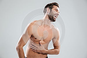 Portrait of a bearded shirtless man doubling up with laughter