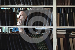 Portrait of bearded thoughtful man strokes beard in bookstore