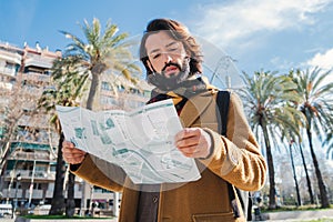 Portrait of bearded tourist male reading a map on Barcelona. Caucasian traveler guy sightseeing and searching locations