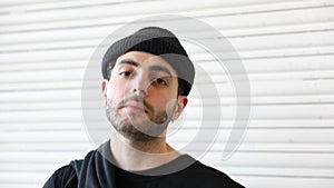 Portrait of bearded young man with cap on his head looking into the camera with pride in slow motion