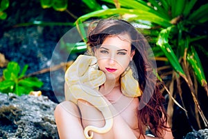 Portrait of the beatiful girl with dangerous snake in the tropic