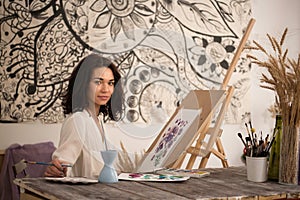 The portrait of beatifull female artist drawing the picture at her studio
