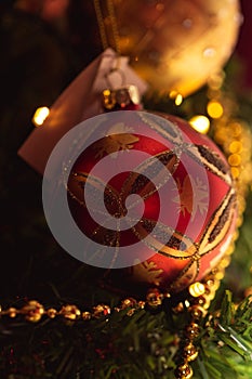 A portrait of a beautifful red christmas ball with sparkling little diamonds on it hanging in a christmas tree. The holiday