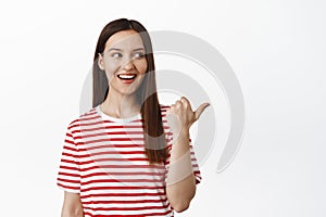 Portrait of beautiful 20s woman pointing finger right, smiling and looking at logo, telling about big sale event