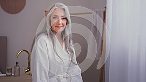 Portrait beautiful 60s old Caucasian 50s senior mature woman standing in bathroom. Grandmother female lady with gray