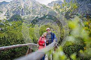 Portrait of beautiful active senior couple hiking together in autumn mountains.