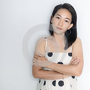 Portrait of beautiful adult 40 years old Asian woman in polka dots dress with arms crossed and pretending straight face over