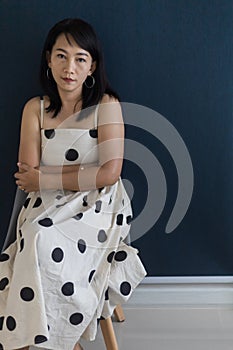 Portrait of a beautiful adult Asian woman 40-year-old with short black hair wearing a polka dot dress, Sitting and pretending