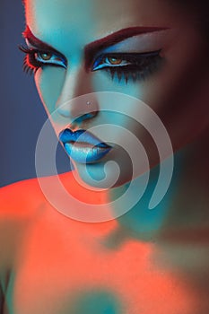 Portrait of beautiful adult woman in red and blue lights and make up