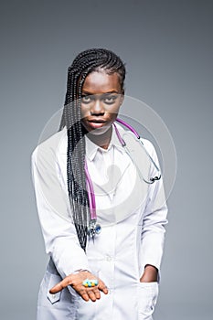 Portrait of beautiful African American doctor or nurse holding prescription drugs isolated over gray background