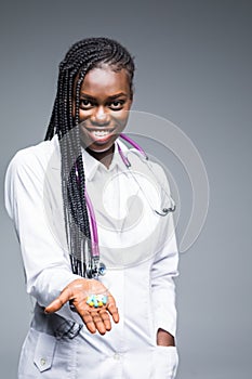 Portrait of beautiful African American doctor or nurse holding prescription drugs isolated over gray background